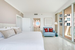 Une chambre d’hôtel moderne, dotée d’un grand lit, d’un canapé et offrant une vue sur l’extérieur grâce à une porte coulissante.