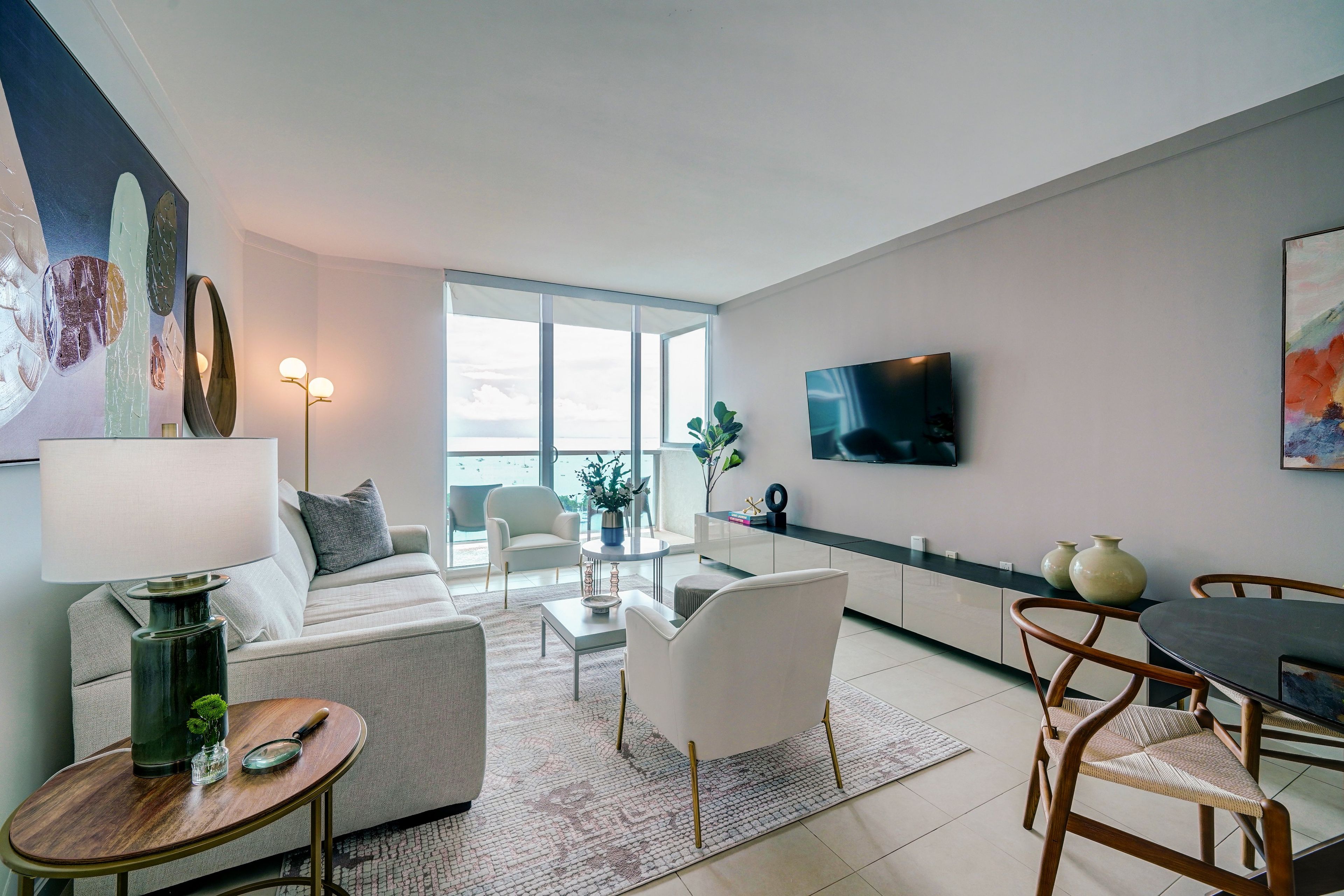 Een moderne woonkamer met een bank, fauteuils, een salontafel en een aan de muur bevestigde televisie.