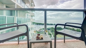 Varanda com mesa posta para refeição, vista para uma marina com barcos e paisagem urbana ao longe.