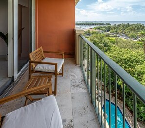 A balcony with two wooden chairs and a table, overlooking a swimming pool and a view of the sea with boats. - Coconut Grove Retreat, Bayviews, 1 Park Incl, Wkspace, Smart TV, Pool/hottub" (Miami)