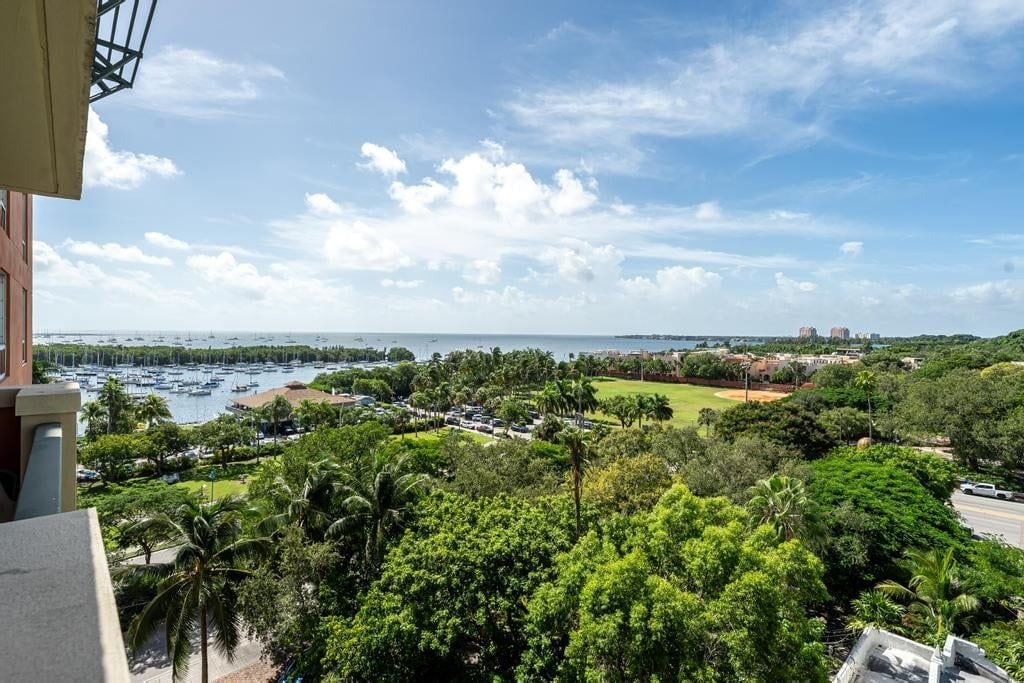 A coastal view with a marina, lush greenery, and a clear sky.