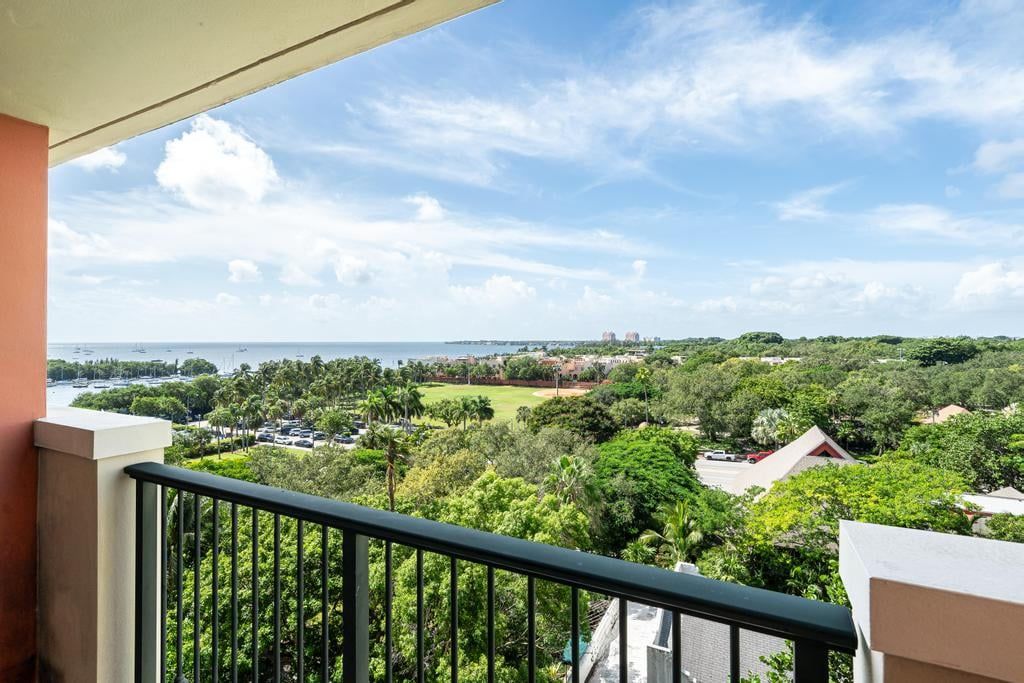 A balcony with a view of a coastal area, including a marina and residential buildings.
