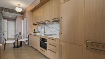 Een moderne keuken met houten kastjes, een marmeren aanrecht en een zithoek met twee stoelen en een tafel.