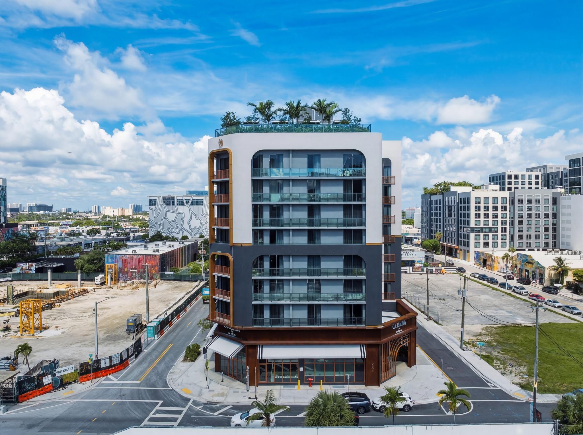 A modern multi-story hotel with a glass facade, a rooftop garden, and a parking area.