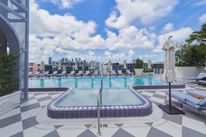 A rooftop pool with lounge chairs and a city skyline in the background. - Designer Studio With Balcony Walk to Restaurants, Art & Nightlife (Miami)