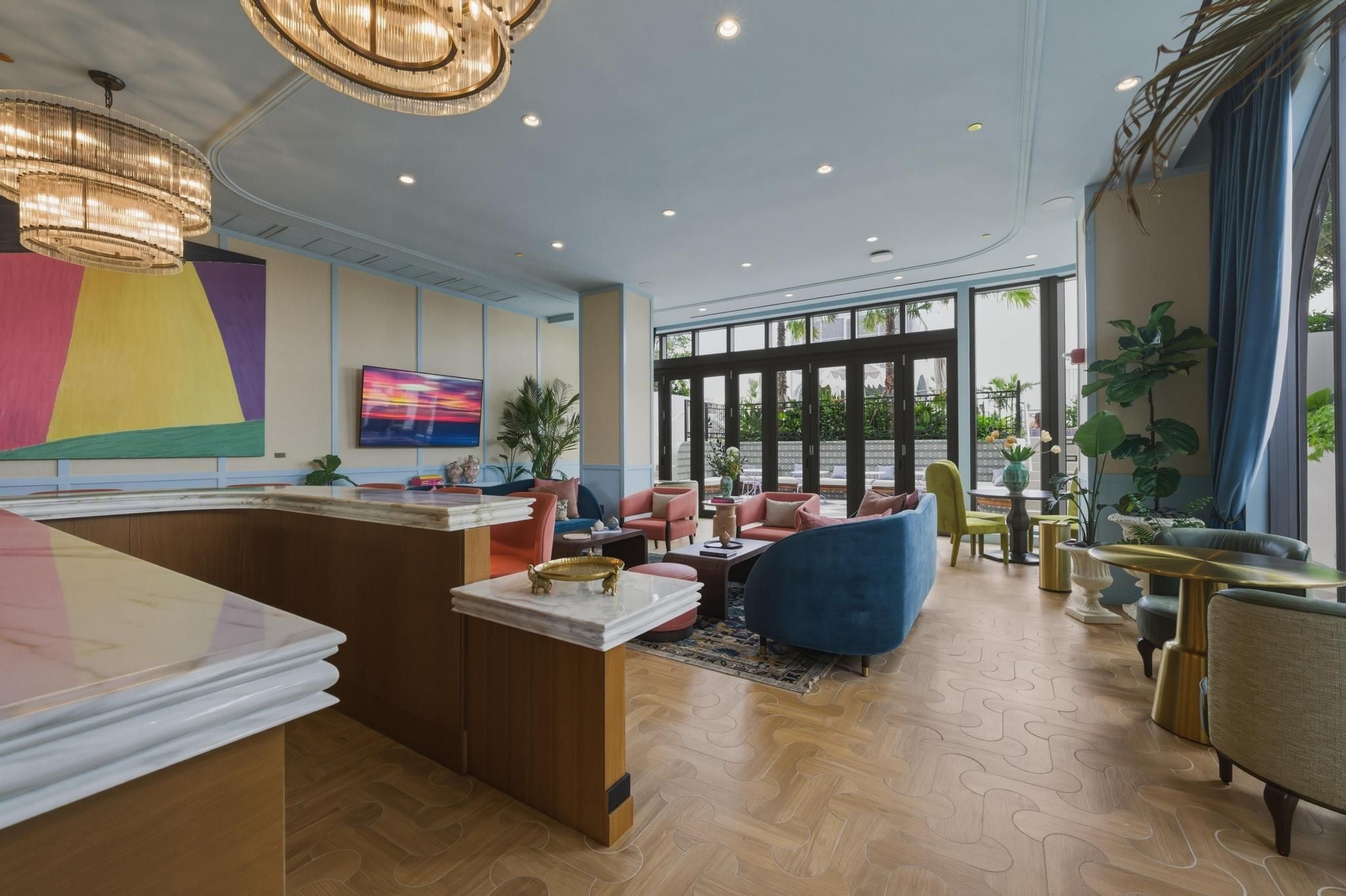 Een moderne hotellobby met een receptiebalie, een zithoek, grote ramen en decoratieve planten.