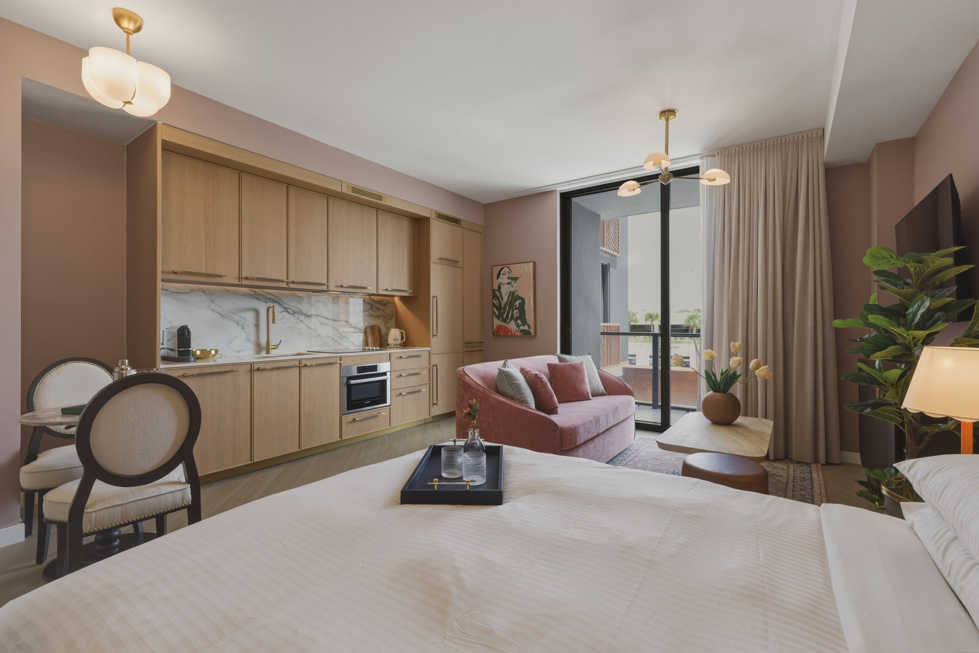 Een hotelkamer met een bed, een zithoek met een bank, een eettafel en een keuken.