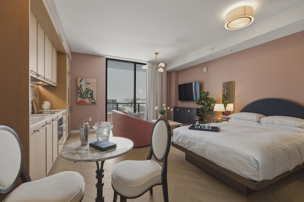 A hotel room with a bed, a dining table, a chair, a TV, and a large window. - Designer Studio With Balcony Walk to Restaurants, Art & Nightlife (Miami)