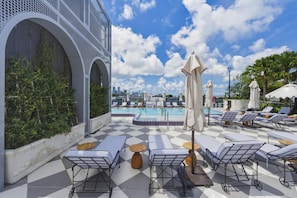 A rooftop pool area with lounge chairs, umbrellas, and a city skyline view. - Designer Studio With Balcony Walk to Restaurants, Art & Nightlife (Miami)