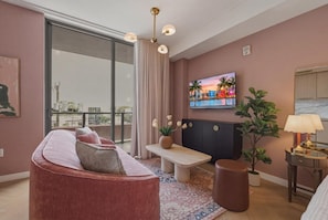A modern living room with a sofa, a bench, a TV, and a plant. - Designer Studio With Balcony Walk to Restaurants, Art & Nightlife (Miami)
