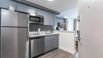 A modern kitchen with stainless steel appliances, grey cabinetry, and a built-in microwave.
