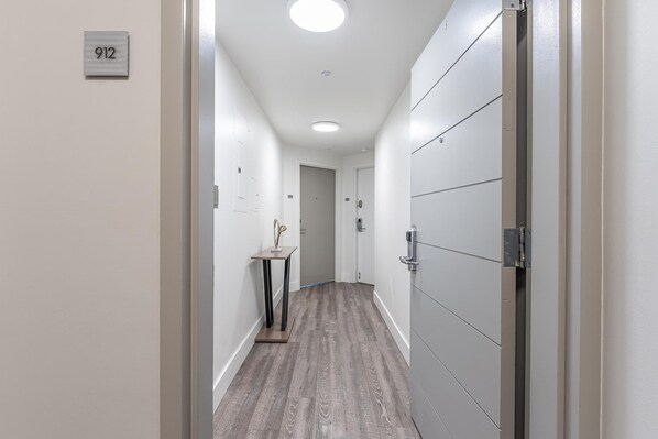 A hallway with a number sign, a door, and a small table with a decorative item. - Connected Hotel Arya Studios 2 Beds, 2 Baths, Kitchen + Free 2-car Parking (Miami)