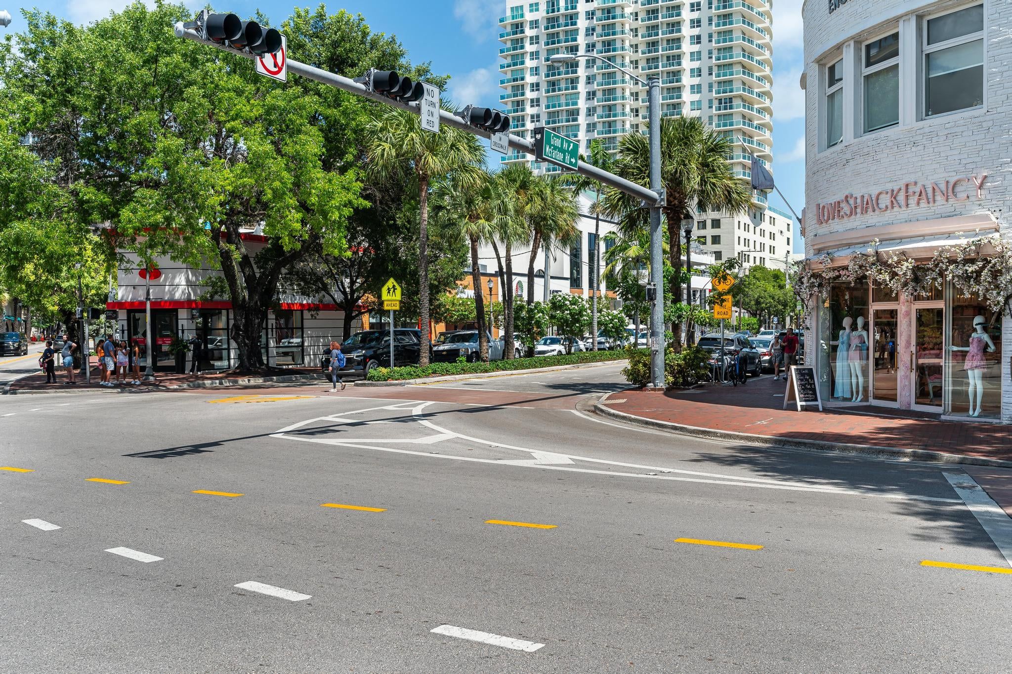 A street intersection with traffic lights, pedestrian crossing, and a building with a storefront.