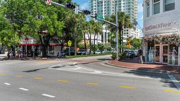A street intersection with traffic lights, pedestrian crossing, and a building with a storefront.