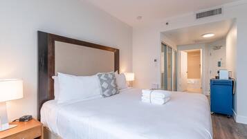 A hotel room with a large bed, a bedside table, a lamp, and a blue cabinet.