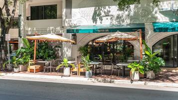 An outdoor cafe with tables and chairs, surrounded by potted plants.
