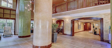 A spacious lobby with high ceilings, large columns, and a grand staircase.