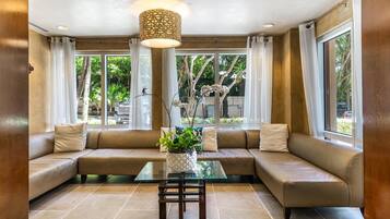 Een moderne woonkamer met een modulaire bank, een glazen salontafel en een potplant.
