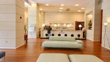 A reception area with a reception desk, a sofa, and a lamp.
