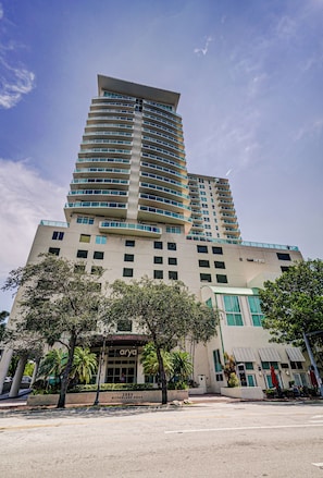 A high-rise hotel with a modern design, featuring multiple balconies and a prominent entrance with a sign.