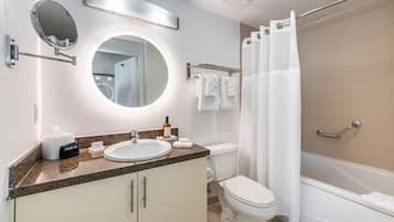 A modern bathroom with a round mirror, a sink, a toilet, and a shower area.