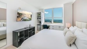 A bedroom with a large bed, a desk, a television mounted on the wall, and a window with a view of the sea. - Coconut Grove: Bayview Unit. Parking Included (Miami)