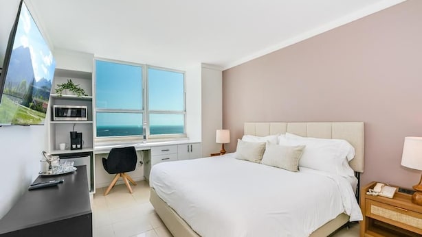 A modern hotel room with a bed, desk, and large window. - Coconut Grove: Bayview Unit. Parking Included (Miami)
