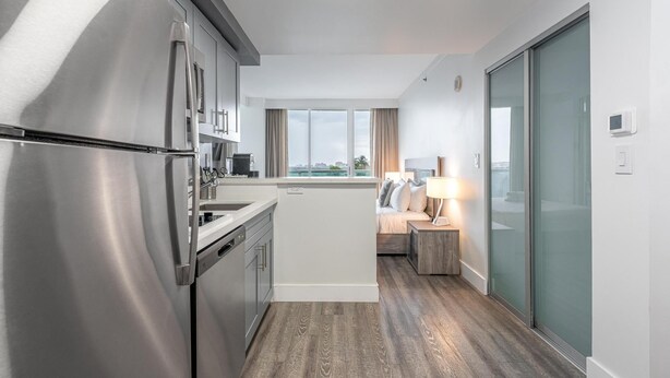 Ett modernt kök med kylskåp, diskmaskin och ett fönster med utsikt över stadsbilden.