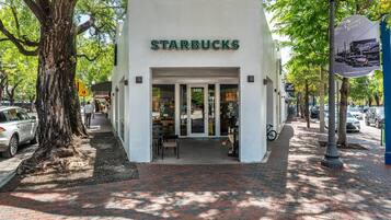 Un Starbucks con fachada blanca, puertas de vidrio y entrada empaveda con ladrillos.