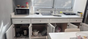 A compact kitchen with a microwave, kettle, and sink. - Tampa Home: 3-Bedroom Condo in Downtown, Near the Beach and Cruise Port (Tampa)