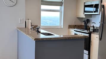 A modern kitchen with a central island, a built-in microwave, and a stainless steel refrigerator.