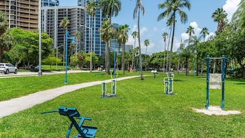 A park with exercise equipment, a pathway, and palm trees.
