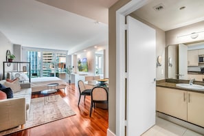 A modern hotel room with a bed, seating area, dining table, and a bathroom with a sink and mirror. - Coconut Grove Studio: Sleeps 4 Includes Parking (Miami)