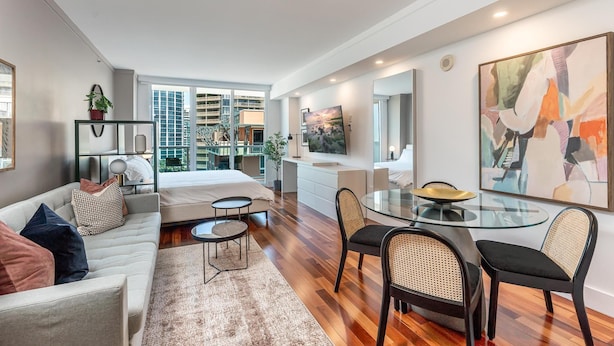 Una habitación de hotel moderna con cama, sofá, mesa de comedor y sillas.