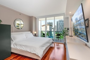 A modern bedroom with a large bed, a round mirror, a balcony with a view of buildings, and a large artwork on the wall. - Coconut Grove Studio: Sleeps 4 Includes Parking (Miami)