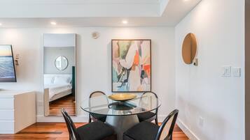 Un comedor moderno con una mesa de vidrio, sillas negras y un cuadro contemporáneo.