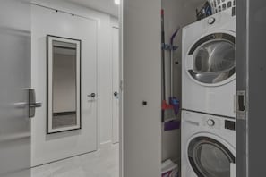 A laundry room with stacked washing machines and a door with a mirror. - Modern Downtown Miami Studio Sleeps 4 Steps to Miami Worldcenter & Arena (Miami)