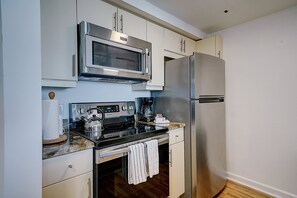 A compact kitchen with a built-in microwave, stainless steel refrigerator, and a gas stove. - Coconut Grove 1/1 Condo Parking Included (Miami)