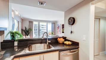 Una cocina moderna con un lavamanos de acero inoxidable, una encimera de madera y vistas a la ciudad a través de amplios ventanales.