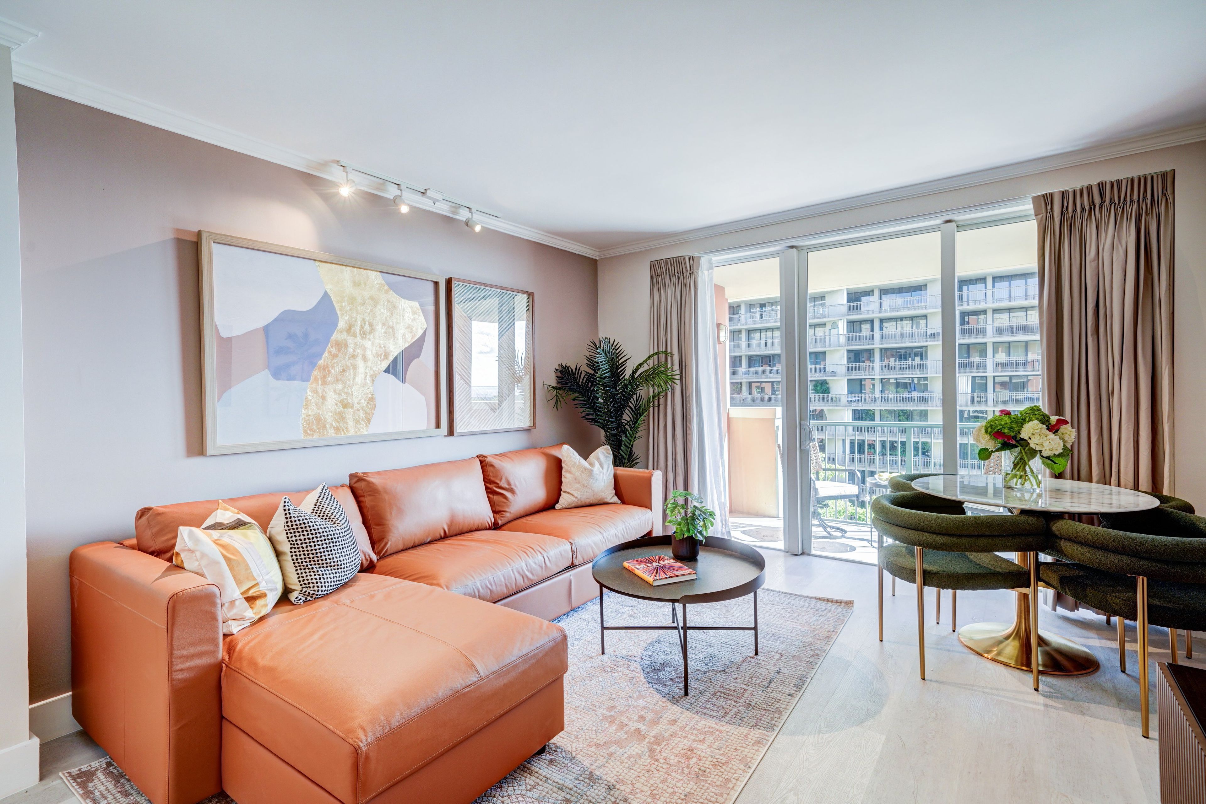 A modern living room with a leather sofa, a coffee table, and a dining area with a glass table and chairs.