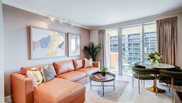 A modern living room with a leather sofa, a coffee table, and a dining area with a glass table and chairs.