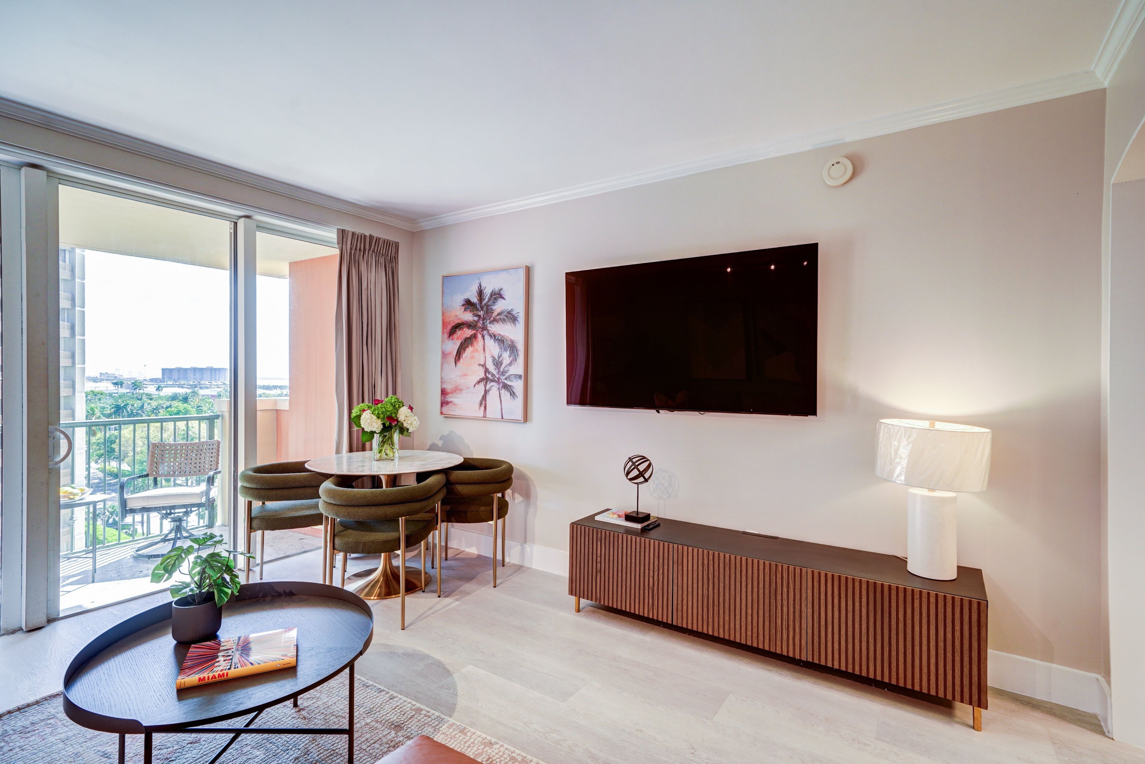 Een moderne woonkamer met een eethoek, een aan de muur bevestigde televisie en een balkon met uitzicht.