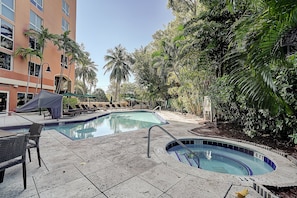 A swimming pool area with lounge chairs and a covered seating area, surrounded by palm trees and a building. - Coconut Grove Beauty! 1/1 Bayview Condo w/ Free Parking (Miami)