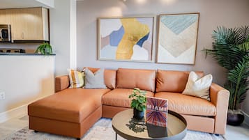 Una sala moderna con un sofá modular, una mesa de centro y dos cuadros abstractos.