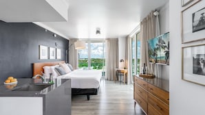 Ett modernt hotellrum med en säng, ett skrivbord, en TV och utsikt över omgivningarna.