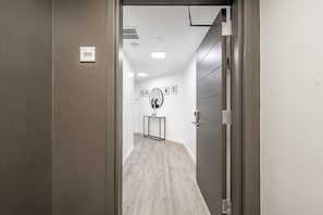 Corredor com porta identificada como '1510', um espelho na parede e um quadro emoldurado.