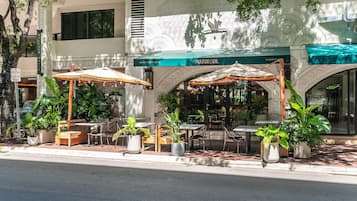 An outdoor cafe with tables and chairs, surrounded by potted plants.