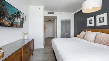 Un dormitorio con una cama, un aparador, un cuadro y una puerta que da a otra habitación.