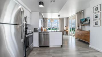 Una cocina moderna con electrodomésticos de acero inoxidable, una isla central y vistas de la ciudad a través de amplias ventanas.
