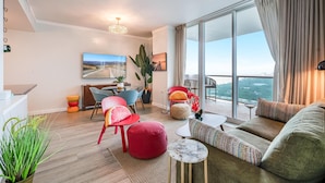 A modern living room with a large window, a dining area, and a balcony with a view. - Bright 1BR in Coconut Grove King Bed, Views, Pool & Parking (Miami)